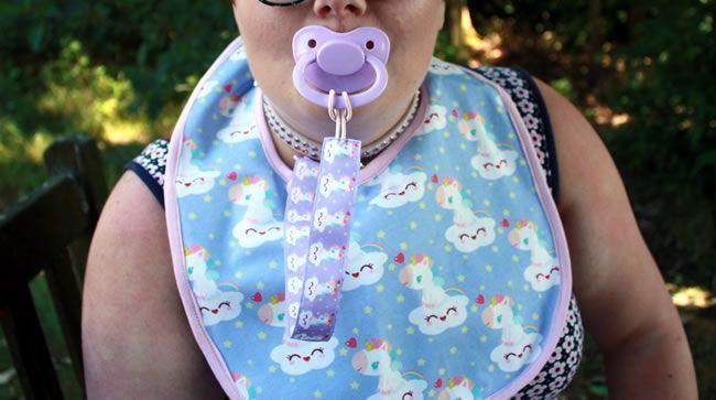 Image showing Little Rae wearing a Bib, pacifier and retainer in public