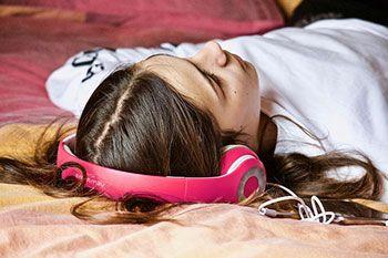 Woman laying on the bed listening through headphones