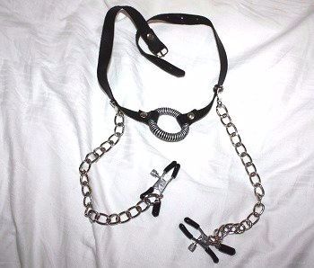 This gag is rather attractive and features  pair of nipple clamps on chains